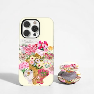 May include: A cream-colored smartphone case and a matching circular phone grip featuring a colorful floral bouquet print. The design includes various flowers in pink, red, yellow, and white, with text that reads, let all that you do be done in love.