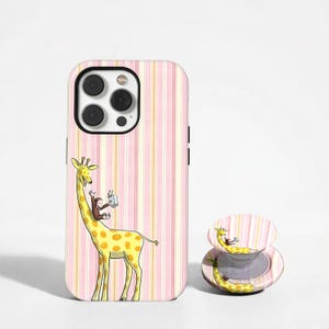 May include: A phone case and phone grip featuring a yellow giraffe with brown spots and a monkey taking a photo. The case has a pink and white striped background.