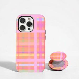 Op de afbeelding: Een smartphonehoesje en een bijpassende inklapbare telefoonhouder met een roze, oranje en geel ruitpatroon van kruisende horizontale en verticale lijnen. Het hoesje heeft een uitsparing voor een camera met drie lenzen.