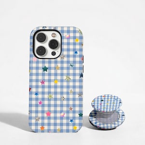 May include: A rectangular smartphone case and a matching circular collapsible phone grip, both featuring a light blue and white gingham check pattern decorated with scattered, multi-colored, and metallic star-shaped accents throughout.