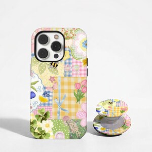 May include: A smartphone case and a matching circular phone grip featuring a colorful collage pattern. The design includes yellow and blue gingham checks, pink tulips, green clover leaves, a small bee, a butterfly, and a jellyfish illustration.