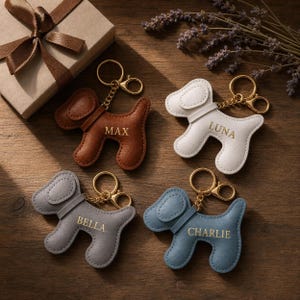 Può includere: Quattro portachiavi a forma di cane in marrone, bianco, grigio e blu. Ogni portachiavi ha una catena e una chiusura color oro. I nomi "MAX", "LUNA", "BELLA" e "CHARLIE" sono stampati sui portachiavi. Una confezione regalo con un nastro marrone sullo sfondo.