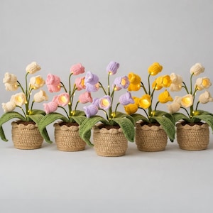 Puede incluir: Seis arreglos florales de ganchillo en macetas tejidas. Las flores son de varios colores, incluyendo crema, rosa, morado y amarillo, con hojas verdes. Cada flor tiene una pequeña luz en su interior, creando un brillo suave.