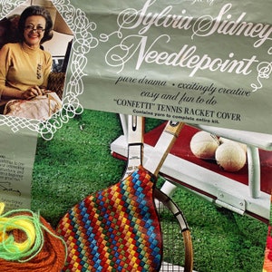 May include: A colorful needlepoint kit for a tennis racket cover. The kit includes yarn in a variety of colors, a needlepoint canvas, and instructions. The kit is titled "CONFETTI" TENNIS RACKET COVER.