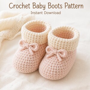 Può includere: Un paio di stivaletti per neonati all'uncinetto fatti a mano in rosa tenue con polsini color crema e delicati dettagli a fiocco. Il testo "Crochet Baby Boots Pattern" e "Instant Download" è visualizzato nella parte superiore dell'immagine. Questi stivaletti sono un affascinante articolo fatto a mano.