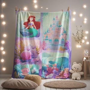 Può includere: Una coperta colorata con un collage di immagini di un popolare film d'animazione. La coperta presenta Ariel la sirena, un castello e scene sottomarine con coralli e conchiglie. La tavolozza dei colori include sfumature di blu, viola e rosa.