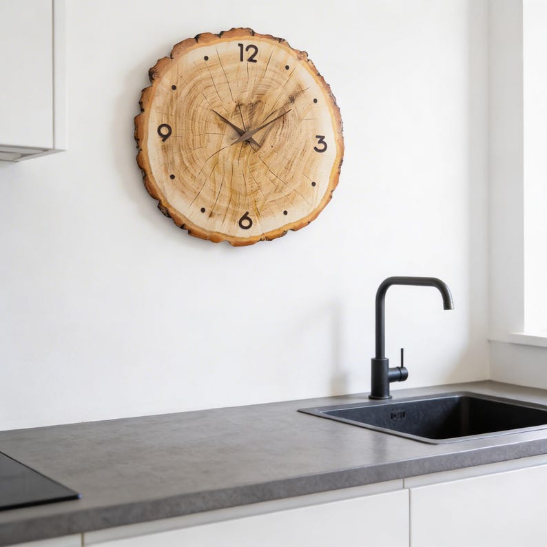 May include: A round wooden clock made from a tree slice, mounted on a white wall. The clock face features black numerals and hands, with the natural wood grain visible. The clock is a decorative element in a kitchen setting.