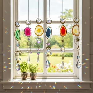 Puede incluir: Una colección de atrapasoles colgantes con rodajas de ágata coloridas y detalles de cristal. Cada atrapasol presenta un diseño único con cadenas de metal dorado, lunas, estrellas y formas geométricas. La decoración de la ventana crea un efecto arcoíris.