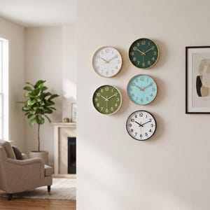 May include: A collection of five circular wall clocks arranged on a wall. The clocks feature various face colors including white, dark green, olive green, light blue, and white with black numerals, each equipped with hour, minute, and second hands.