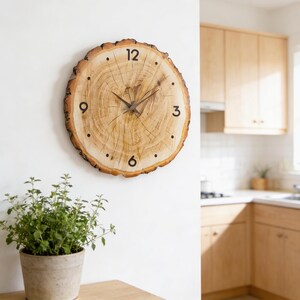 May include: A round wooden clock made from a cross-section of a tree trunk. The clock face features black numerals at the 12, 3, 6, and 9 o'clock positions, with dots marking the other hours. The clock hands are dark brown.