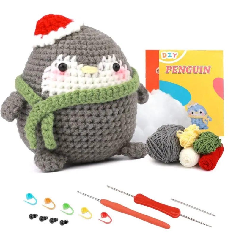 May include: A crocheted penguin wearing a red Santa hat and green scarf. The DIY kit includes yarn in various colors, crochet hooks, stitch markers, and a booklet with the word "Penguin".
