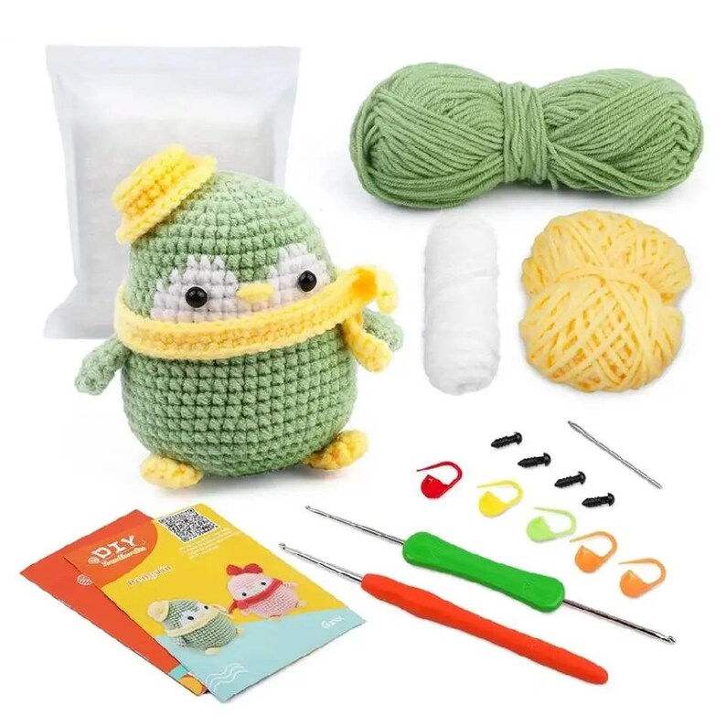 May include: A crochet penguin kit with green, yellow, and white yarn, a crochet hook, and a DIY instruction booklet. The finished penguin has a green body, yellow hat and scarf, and white accents. Includes stuffing, stitch markers, and safety eyes.