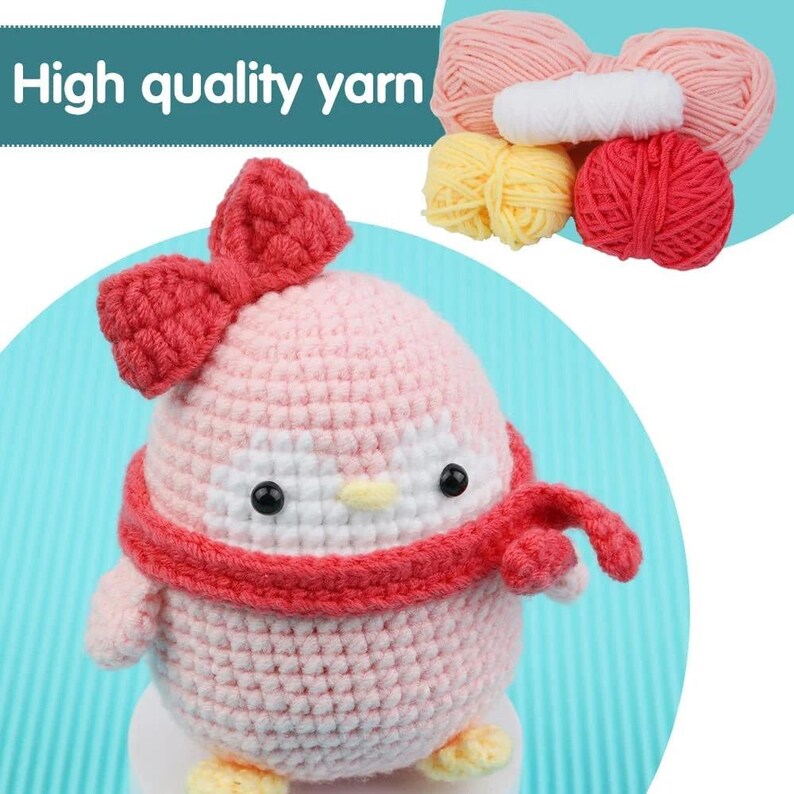 May include: A crocheted penguin with a red bow, scarf, and yellow feet. The penguin is pink and white with black eyes and a yellow beak. The image also shows several balls of yarn in pink, yellow, and red. Text in the image reads "High quality yarn."