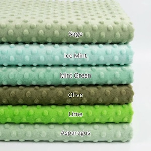 Op de afbeelding: Een stapel van zes groene, getextureerde stoffen, variërend van licht naar donker. De kleuren zijn Salie, Ice Mint, Mintgroen, Olijf, Limoen en Asperge. Elke stof heeft een bobbelig oppervlak en een zacht, pluche uiterlijk. De namen van de kleuren staan op elke stof.