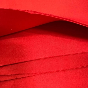 May include: Close-up of bright red fabric, folded to reveal layers. The fabric has a smooth texture and a vibrant color, with visible stitching along the edges. The image highlights the material's depth and texture, suitable for apparel or craft projects.