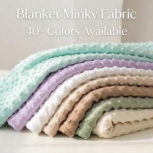 May include: A stack of soft minky fabric blankets in various pastel colors, including mint green, lavender, white, and beige. The blankets have a textured, dotted surface. Text reads "Blanket Minky Fabric 40+ Colors Available."