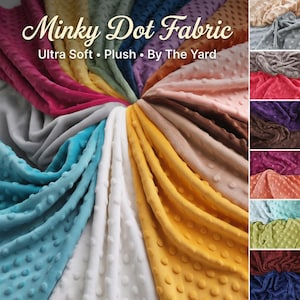 Puede incluir: Una colección de muestras de tela Minky Dot de colores variados, incluyendo rosa, azul, amarillo y blanco. La tela es ultra suave y afelpada, con una textura de puntos. La imagen incluye el texto "Minky Dot Fabric" y "Ultra Soft • Plush • By The Yard."