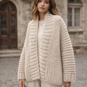 Puede incluir: Un c&aacute;rdigan color crema con frente abierto y un dise&ntilde;o de punto grueso. El su&eacute;ter presenta un cuello chal y detalles acanalados a lo largo de los bordes y las mangas. El c&aacute;rdigan est&aacute; hecho de un material suave y c&aacute;lido.