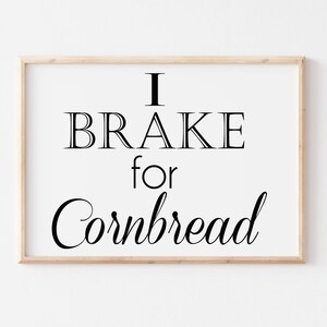 Puede incluir: Una impresión enmarcada con el texto "I BRAKE for Cornbread" en fuente negra sobre fondo blanco.