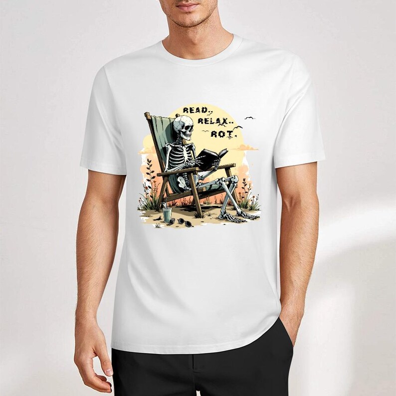 White t-shirt featuring a skeleton reading a book while relaxing in a beach chair. The graphic includes the text "Read, Relax, Rot." The skeleton is depicted in a sunny outdoor setting.