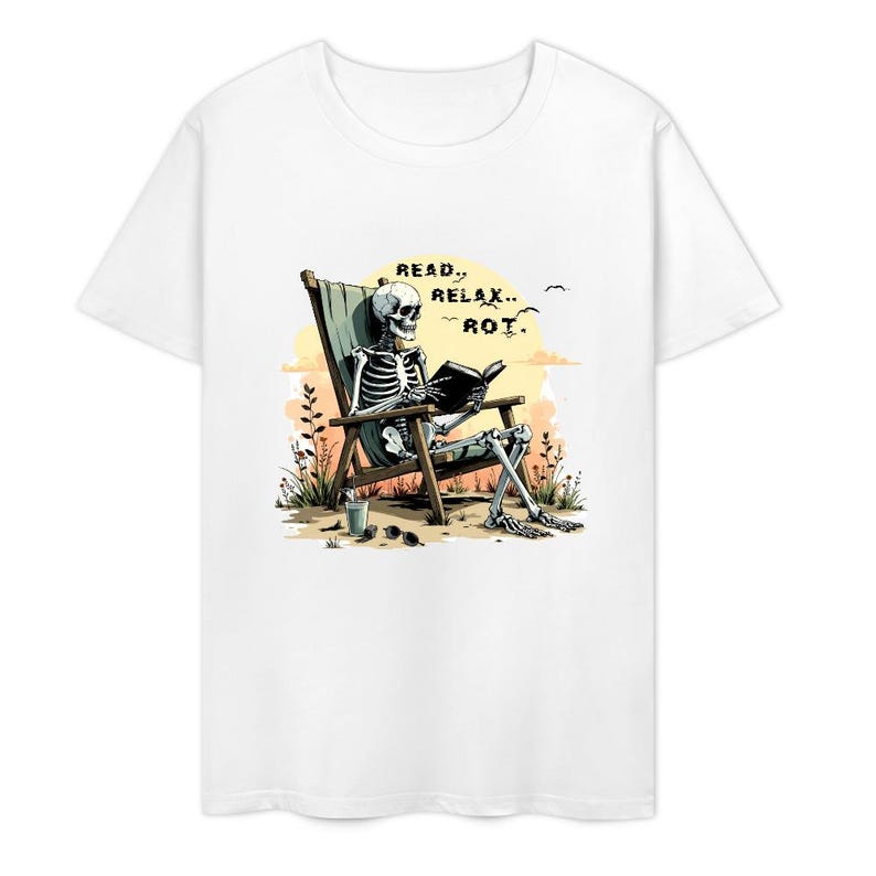 White t-shirt featuring a skeleton relaxing in a beach chair, reading a book. The graphic includes the words "READ, RELAX, ROT." Sunglasses and a drink are next to the chair. The background shows a sunset and birds.