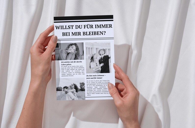 Pode incluir: Um cart&atilde;o impresso em preto e branco segurado por m&atilde;os, com o texto "WILLST DU F&Uuml;R IMMER BEI MIR BLEIBEN?" e imagens. O cart&atilde;o tem uma borda preta e est&aacute; sobre um fundo branco.