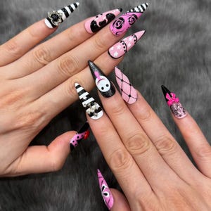 May include: Stiletto-shaped press-on nails featuring a variety of designs including black and white stripes, pink and black floral patterns, white stars on pink, a character face, black fishnet patterns, and small decorative rhinestones and bows.