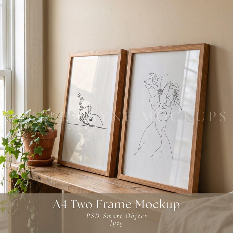 May include: Two framed art prints with wooden frames. One print shows a line drawing of a hand holding a cup, the other a woman's face with a flower crown. The frames are displayed on a wooden shelf.