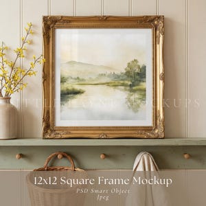 May include: A gold ornate framed 12x12 inch square mockup featuring a watercolor landscape painting of a lake and mountains. The frame is displayed on a green shelf with a basket and a vase of yellow flowers.