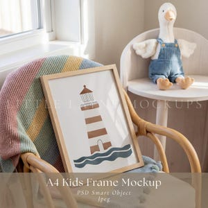 May include: A framed A4 kids' mockup with a lighthouse illustration in brown and white. The frame is light wood. A plush goose toy in blue overalls sits on a small white chair. The scene includes a colorful blanket. The frame size is approximately 21 x 30 cm.