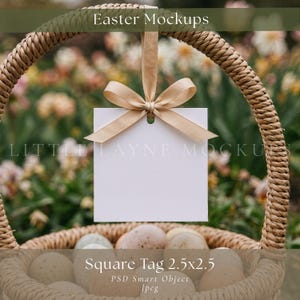 May include: A woven basket with a square white tag hanging from a beige ribbon. The tag is 2.5 x 2.5 inches. The basket contains several speckled eggs. The words "Easter Mockups" and "Square Tag 2.5x2.5" are visible.