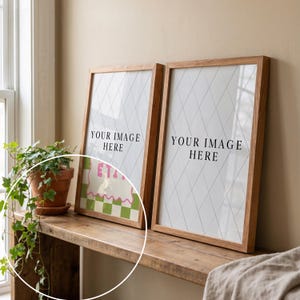 May include: Two framed prints with wooden frames, each displaying the text "YOUR IMAGE HERE" on a white background with a diamond pattern. One print features a colorful graphic with the text "ETA". A potted plant sits on a wooden shelf.