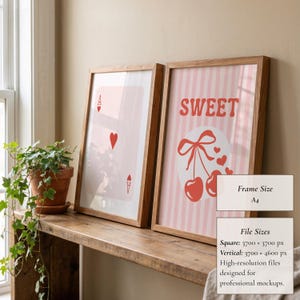 May include: Two framed art prints. One shows an Ace of Hearts playing card, the other says "SWEET" with cherries and hearts. Both are in light wood frames. The prints are displayed on a wooden shelf with a potted plant.
