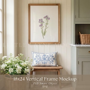 May include: A framed botanical print with purple flowers and green stems. A blue and white floral cushion rests on a wooden bench below. A basket of white flowers is on the left.