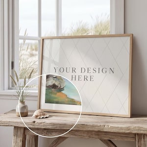 May include: A framed print with the text "YOUR DESIGN HERE" on a rustic wooden table. The artwork features a watercolor landscape. A seashell and a small vase with dried plants are also on the table.