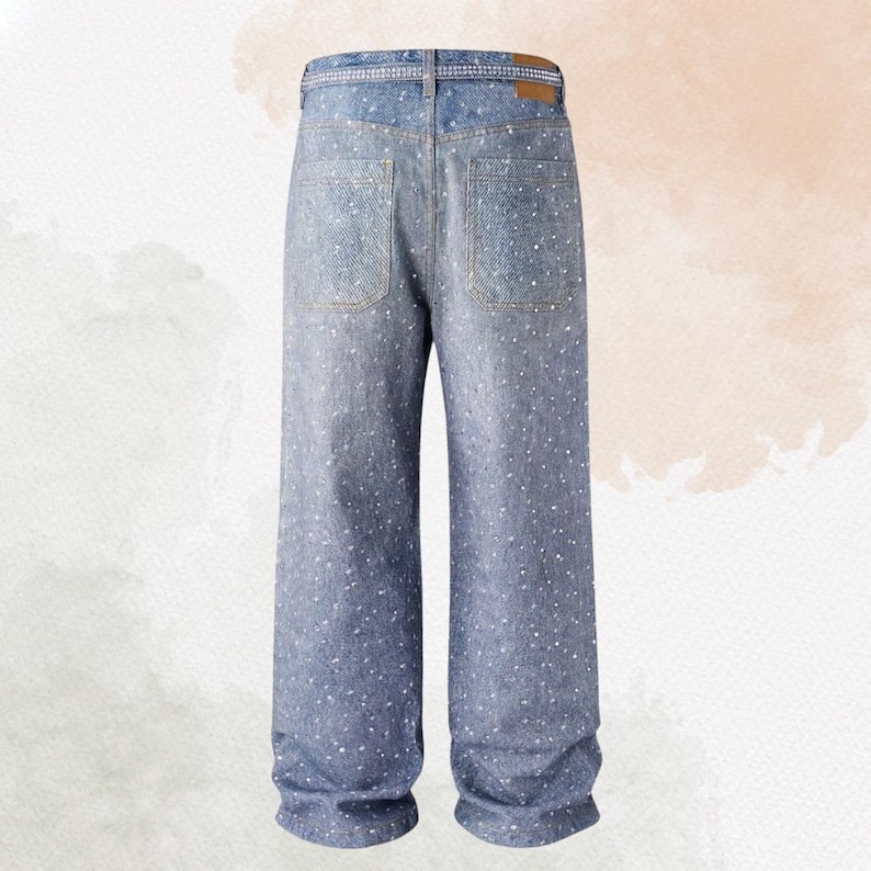 May include: Light blue denim jeans with a wide leg design. The jeans feature a scattering of white embellishments across the fabric. The back view shows two pockets and a brown leather patch on the waistband.