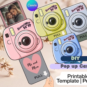 May include: A collection of DIY pop-up cards in the shape of retro cameras. The cards are in pink, yellow, blue, and gray, each with the text "Guess Who Is It". The pink card has a photo of a mother and child.