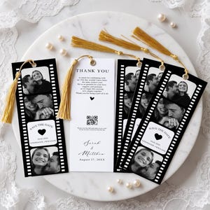May include: Four rectangular bookmarks with gold tassels. Three bookmarks feature black and white film strip designs with couple photos and 'SAVE THE DATE 10.02.2026 STEPHANIE + WILLIAM' text. One white bookmark reads 'THANK YOU' with a QR code and names.