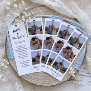 May include: Four rectangular paper bookmarks with light blue tassels, featuring photos of a couple in front of a church, the names Justin & Margaret, the date July 2, 2026, and the text of Numbers 6:24-26 printed in black ink on white cardstock.