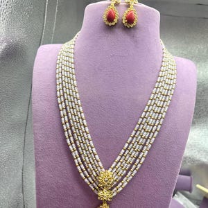 Traditionellt indiskt haramhalsband med 5 raden pärla med rubinröda stenar och matchande blommiga örhängen.