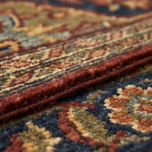 May include: Close-up of a section of a patterned rug. The rug features a rich color palette of deep reds, blues, greens, and golds. The intricate design includes floral and geometric elements, with a textured, woven appearance.