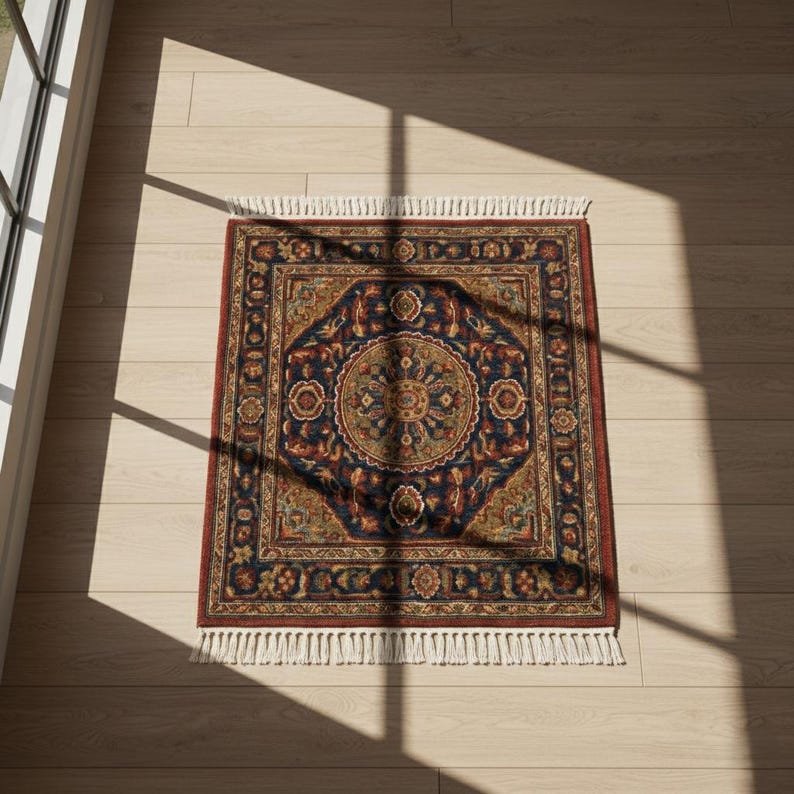 May include: A square, ornate rug with a central medallion design. The rug features a navy blue background with intricate patterns in shades of red, gold, and green. It has a red border and white fringe.