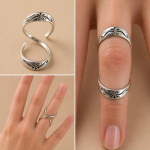 K&ouml;nnte beinhalten: Silberfarbene Ringe mit einem dekorativen schwarzen Filigranmuster. Ein Ring ist ein Doppelband, die anderen sind Einzelb&auml;nder. Die Ringe werden an einem Finger und auch separat gezeigt.