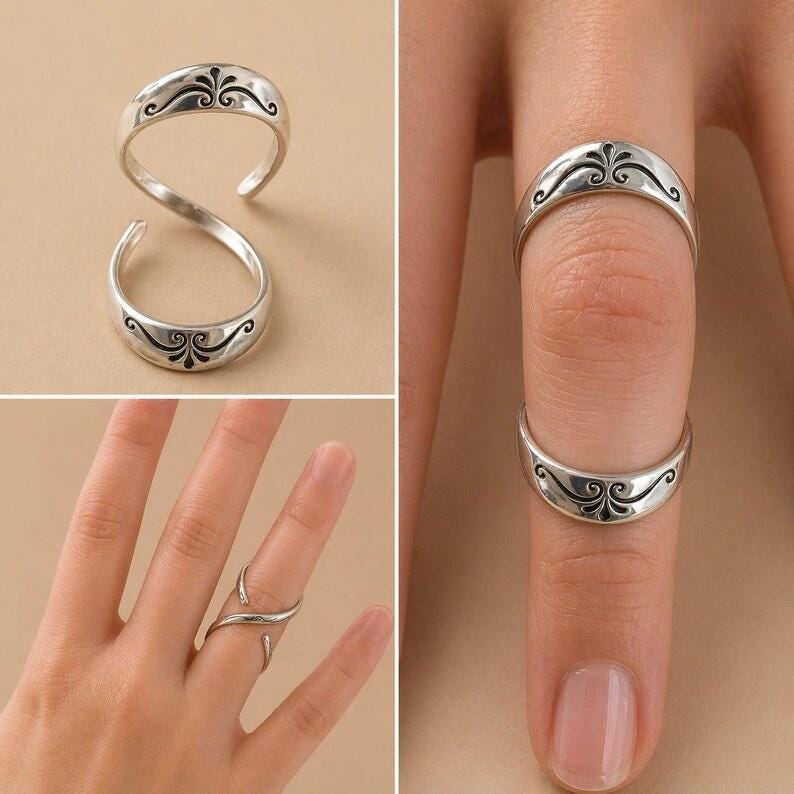 K&ouml;nnte beinhalten: Silberfarbene Ringe mit einem dekorativen schwarzen Filigranmuster. Ein Ring ist ein Doppelband, die anderen sind Einzelb&auml;nder. Die Ringe werden an einem Finger und auch separat gezeigt.
