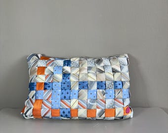 Op de afbeelding: Rechthoekig kussen geweven van patronen stropdassen in blauw, oranje en crème. Het ontwerp heeft een dambordpatroon, met de verschillende stropdasstoffen. Een uniek woondecoratie-item, ongeveer 40 cm x 25 cm.