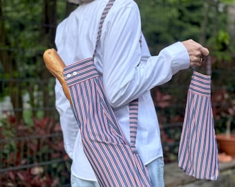 Set regalo per picnic con vino: sacchetto in baguette e sacchetto portabottiglie, a righe blu e rosse, realizzato con materiali riciclati.