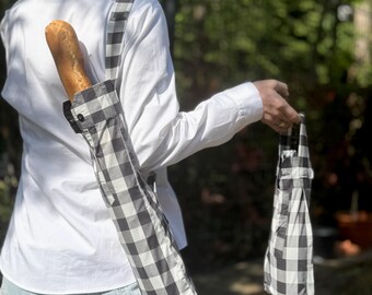 Op de afbeelding: Een zwart-wit geruite baguette tas en een bijpassende kleine tas. De baguette tas wordt over de schouder gedragen en bevat een brood. De tassen zijn gemaakt van stof en hebben een klassiek ruitpatroon.