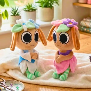 May include: Two plush dolls with large eyes, flower crowns, and long ears. One doll wears a blue and white outfit, the other a pink dress. Both have green and white striped legs and arms crossed.
