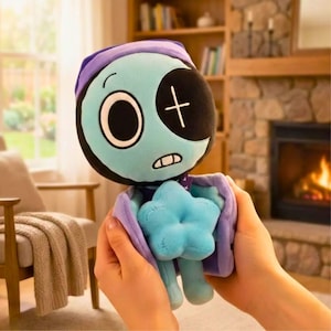 Pu&ograve; includere: Bambola di peluche con viso turchese, benda sull'occhio nera e cappello viola. La bambola ha un oggetto a forma di stella blu tra le braccia ed &egrave; tenuta da due mani. Lo sfondo include un camino e una libreria.