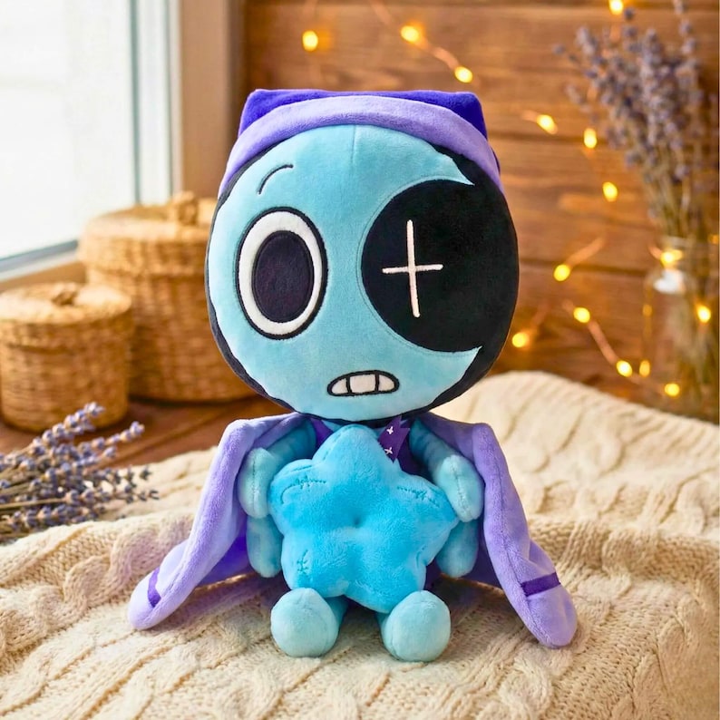 Pu&ograve; includere: Un peluche a forma di personaggio dei cartoni animati con un viso blu, una benda sull'occhio nera e un cappello e un mantello viola. Il personaggio tiene in mano una stella blu. Lo sfondo comprende una finestra, cesti e luci decorative.